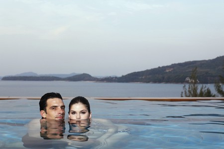 Man and woman in pool, heads half submerged in waterの写真素材