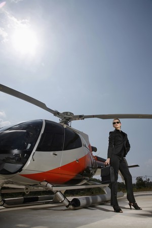 Businesswoman with sunglasses standing beside helicopterの写真素材