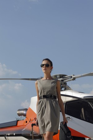 Businesswoman with luggage and briefcase standing by the helicopterの写真素材