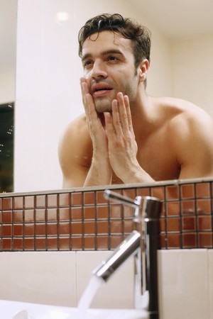Man examining his face in the mirror