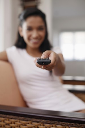 Woman switching channel with remote controlの写真素材