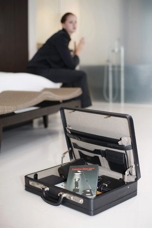 Businesswoman sitting on bed contemplating, focus on book in briefcaseの写真素材