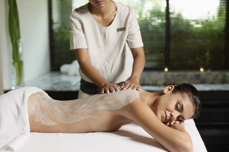 Woman receiving back massage with coconut scrubの写真素材