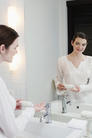 Woman pouring lotion onto her palmの写真素材