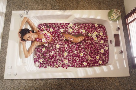 Woman relaxing in bathtub with flower petalsの写真素材