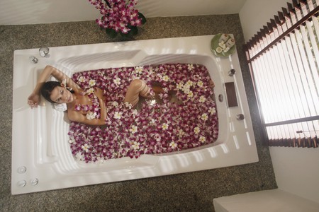 Woman relaxing in bathtub with flower petals