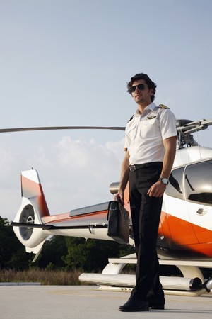 Pilot holding briefcase with helicopter in the background
