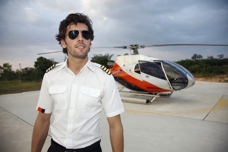 Pilot with sunglasses standing in front of helicopterの写真素材