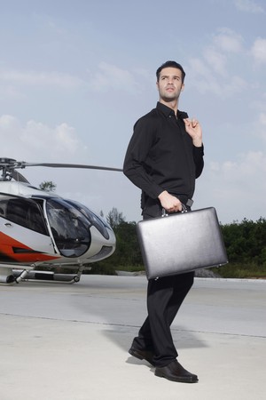 Businessman holding briefcase standing at helipadの写真素材