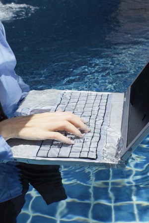 Businesswoman using laptop in swimming poolの写真素材