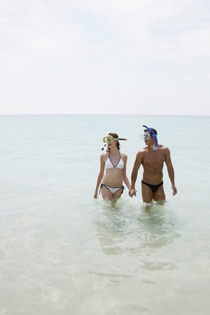Man and woman with snorkeling gear on beachの写真素材