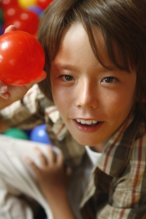 Boy holding up a red ballの写真素材