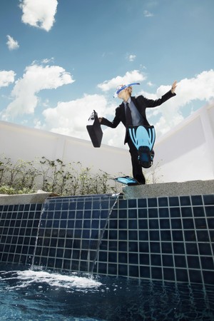 Businesswoman with scuba gear on jumping into swimming poolの写真素材