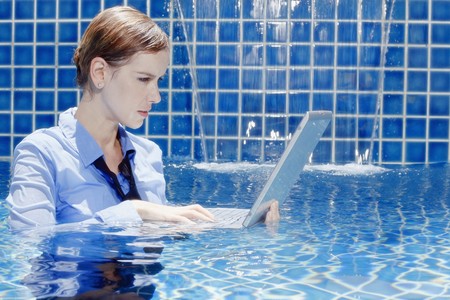 Businesswoman using laptop in swimming poolの写真素材