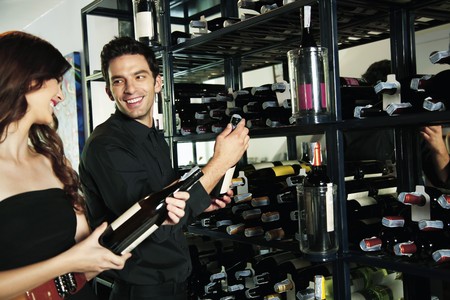 Man and woman selecting wine bottles from rackの写真素材