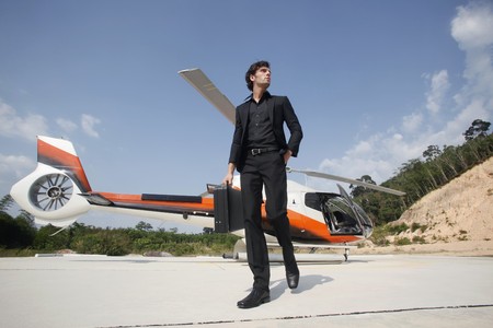 Businessman holding briefcase walking away from helicopterの写真素材