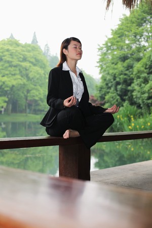 Businesswoman meditating on benchの写真素材