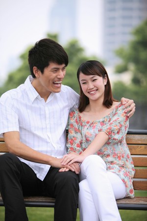 Man and woman sitting on a bench, smilingの写真素材