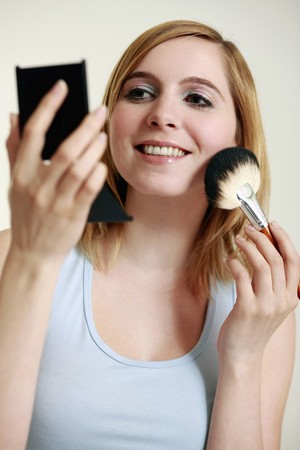 Woman applying blusher on her cheeksの写真素材