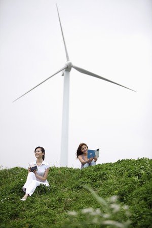 Women reading outdoors with wind mill in the backgroundの写真素材