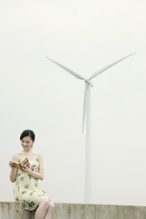 Woman reading outdoors with wind mill in the backgroundの写真素材