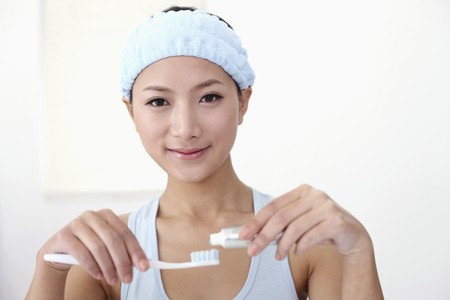Woman squeezing toothpaste onto toothbrushの写真素材