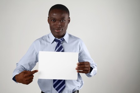 Businessman holding up a piece of blank paper and pointing at itの写真素材