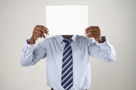 Businessman holding up a piece of blank paper, covering his faceの写真素材