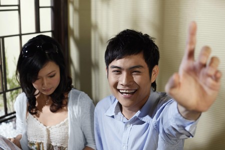 Man gesturing to order food, woman reading menuの写真素材