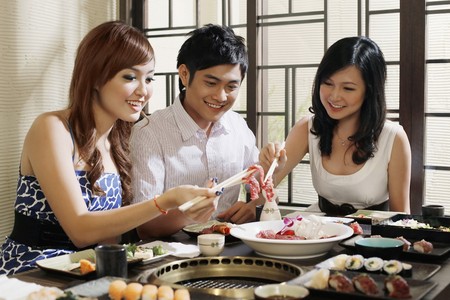 Man and women enjoying food in a japanese restaurantの写真素材