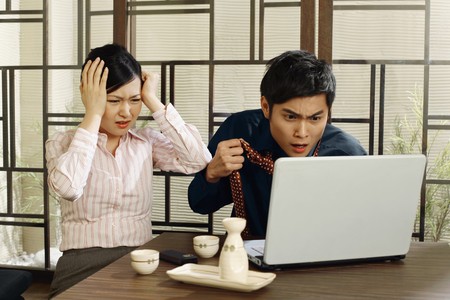 Business people looking at laptop in dismayの写真素材