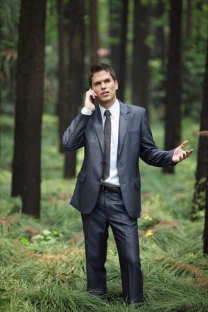 Businessman talking on the phone in forestの写真素材