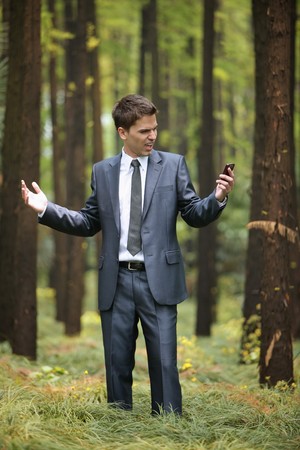 Businessman with mobile phone in forestの写真素材