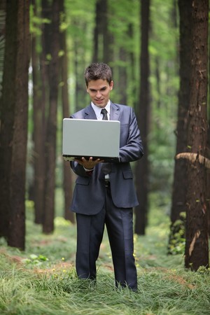 Businessman using laptop in forestの写真素材