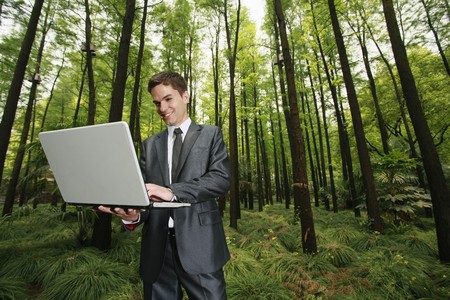 Businessman using laptop in the forestの写真素材