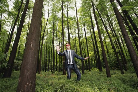 Businessman with blindfold walking aimlessly in the forestの写真素材