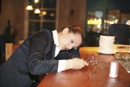Drunk businesswoman sleeping on bar counterの写真素材