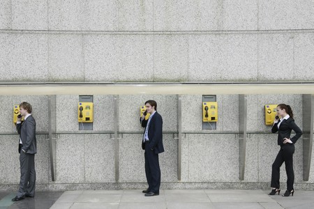 Business people using public telephonesの写真素材
