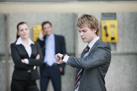 Business people waiting for businessman talking on public telephone