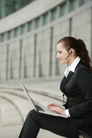 Businesswoman with headset using laptopの写真素材