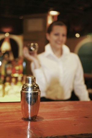 Businesswoman preparing cocktail, focus on cocktail shaker in the foregroundの写真素材