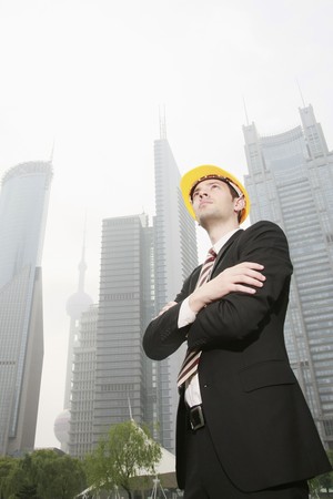 Businessman wearing safety hat with arms crossedの写真素材