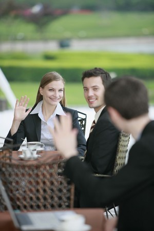 Business people waving at each other at outdoor cafeの写真素材