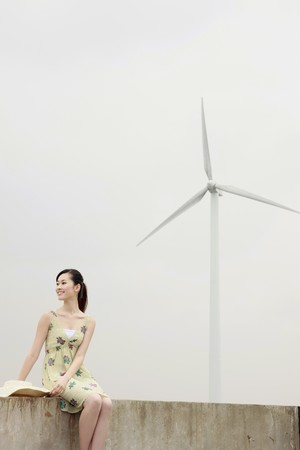 Woman relaxing outdoors with wind mill in the backgroundの写真素材