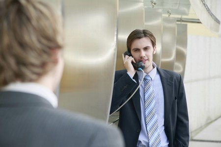 Businessmen using public telephonesの写真素材