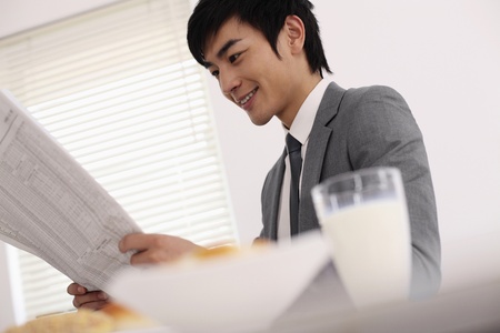 Man reading newspaper over breakfastの写真素材