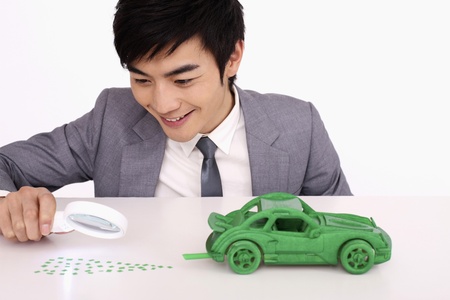 Man using magnifying glass to look at green exhaust waste