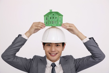 Man balancing green house model on safety helmetの写真素材