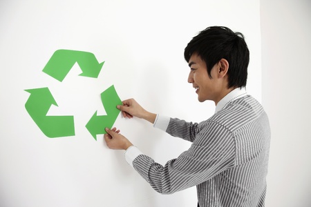 Man adjusting recycling symbol on the wallの写真素材