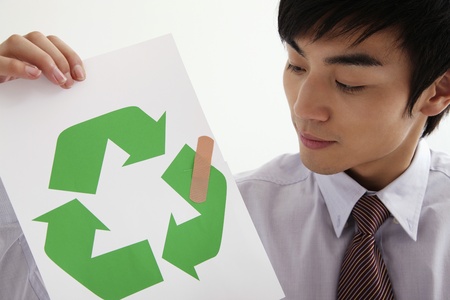 Man holding paper with bandage on recycling symbolの写真素材